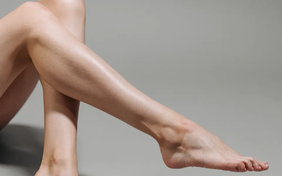 Jambes à la peau lisse et uniforme après épilation, sur fond clair