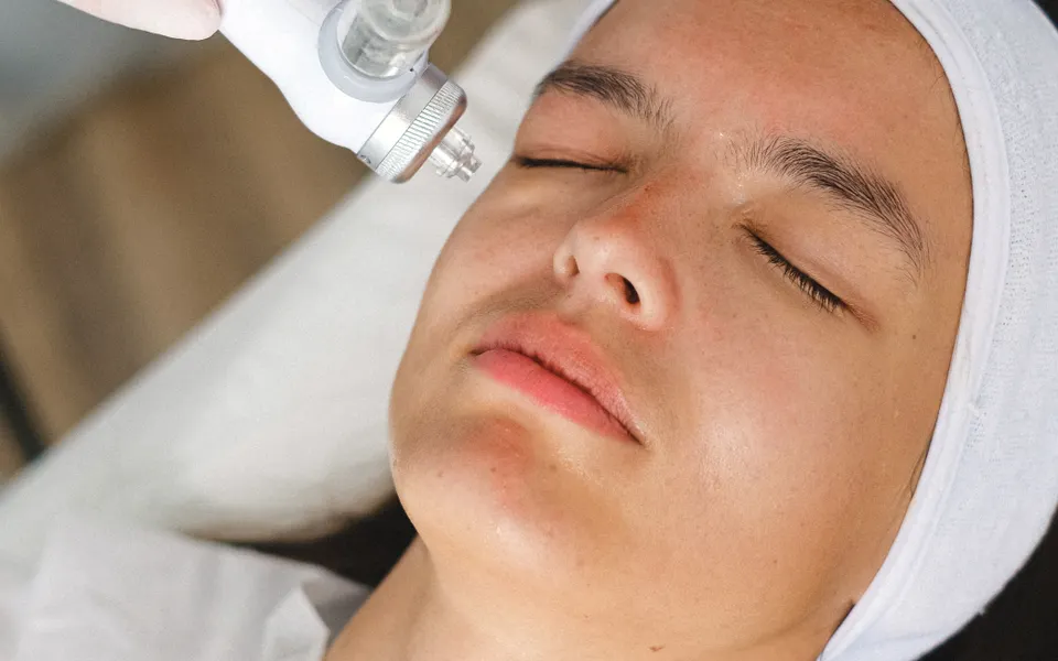 Pièce à main professionnelle passée sur le visage d’une cliente allongée en cabine